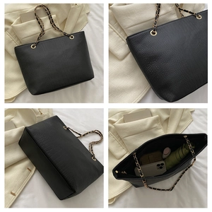 Detail of black crocodile texture tote with gold chain strap and spacious interior storage