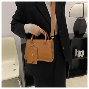 Détail du cabas en cuir verni marron avec large bandoulière et pochette assortie