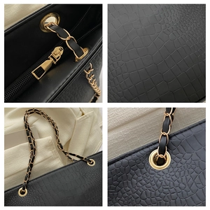 Detail of black crocodile pattern leather bag with gold hardware and chain strap