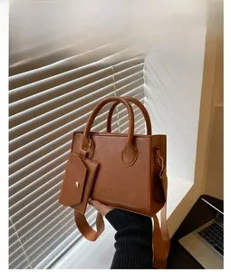 Détail d'un cabas en cuir verni marron avec lettrage doré et pochette à cartes assortie