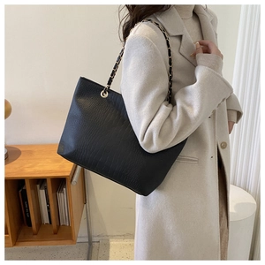 Detail of black faux crocodile leather tote bag with elegant chain shoulder strap