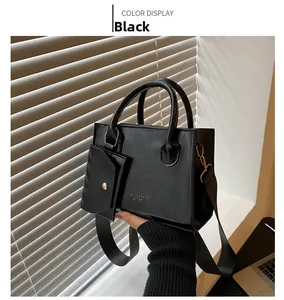 Détail du sac carré en cuir noir mat avec logo doré et bandoulière en tissu épais