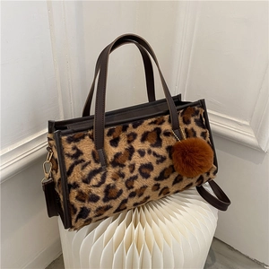 Faux fur leopard print tote bag with brown leather handles and decorative pom-pom charm