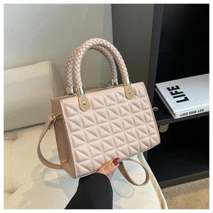 Close-up of quilted nude pink crossbody bag with woven handle on a white sofa