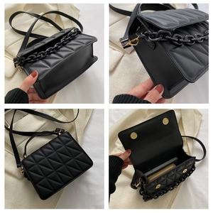 Detail view of black quilted crossbody bag with gold hardware and internal storage space