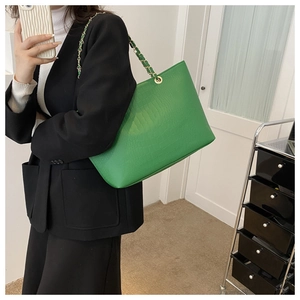 Fashionable green tote bag with crocodile pattern and chain strap shown on model