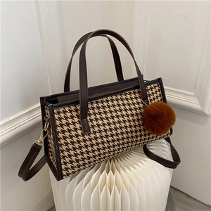 Classic houndstooth tote bag with brown leather trim and plush pompom charm accessory
