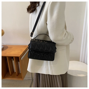 Close-up of black quilted shoulder bag featuring geometric stitching and chain detail