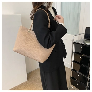 Detail of beige faux leather tote bag with crocodile texture and gold chain strap