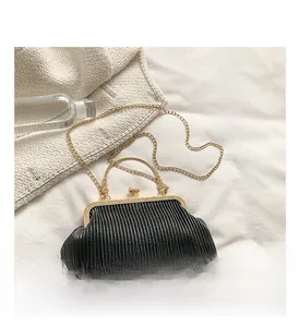 Detail der schwarzen Plissee-Clutch mit Retro-Goldbeschlägen und einem Kettenriemen