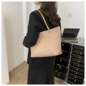 Detailed view of beige crocodile embossed tote bag with gold chain strap on shoulder