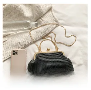 Details der schwarzen Cloud-Tasche mit Falten, Goldrahmen und Kette auf weißem Stoff