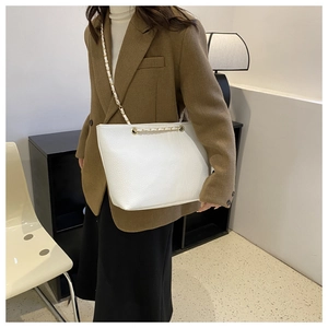 Detail of white crocodile texture leather tote bag with gold chain shoulder strap