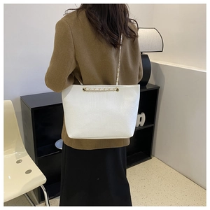 Close-up of white crocodile pattern tote bag featuring elegant golden metal chain strap