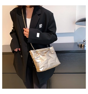 Detail der gesteppten goldenen Metallic-Oberfläche und des eleganten Kettenriemens der Tasche