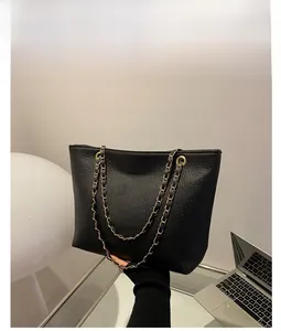 Detail of black faux crocodile leather tote bag featuring gold chain strap and texture