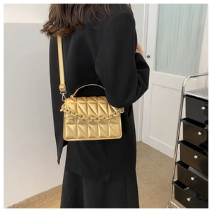 Modern gold crossbody bag with geometric quilting and chunky chain shown on model