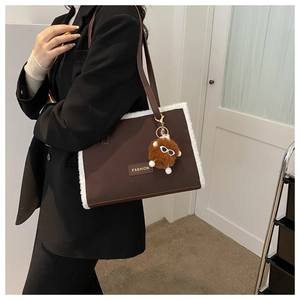 Détail d'un grand sac fourre-tout marron avec bordure en fourrure et pendentif peluche
