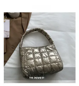 Macro shot of champagne gold quilted puffer handbag featuring square stitched embroidery