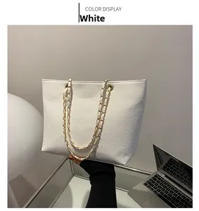 Close-up of white crocodile pattern tote bag with gold chain strap for women