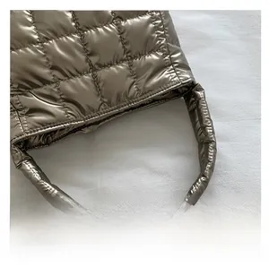 Close-up of padded quilted handle on bronze metallic puffer tote bag with square stitching