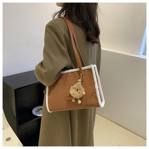 Détail du sac fourre-tout marron avec bordure en peau de mouton blanche et pompon