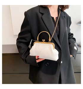 Detailansicht der weißen Falten-Tasche mit goldener Schließe und Kette auf schwarzem Blazer