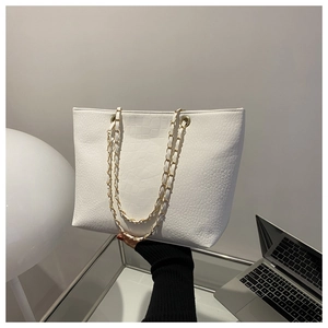 Close-up of white tote bag with crocodile texture and gold chain strap detail