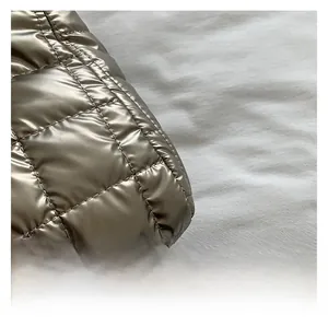 Close-up of metallic quilted texture and stitching detail on the golden handbag
