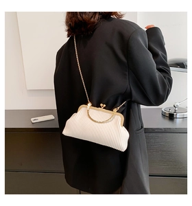 Detail einer beigen Falten-Umhängetasche mit Goldkette auf einem schwarzen Blazer-Outfit