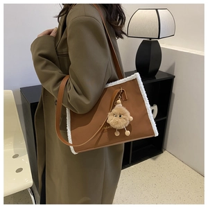 Détail du cabas en cuir marron avec bordure en fausse fourrure blanche et charm peluche