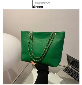 Close-up of green crocodile embossed leather tote bag with elegant gold chain handle