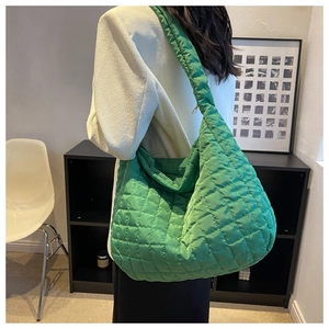 Detail of emerald green quilted shoulder bag showing large capacity and puffy nylon texture