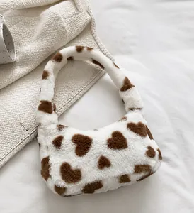 Close-up of fluffy white faux fur handbag featuring soft brown heart patterns and plush texture