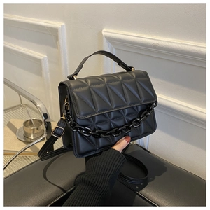 Close-up of black quilted small square bag with V-pattern and gold hardware details