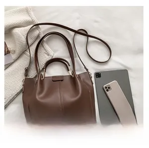 Detail view of large brown tote bag showing spacious interior with tablet and phone
