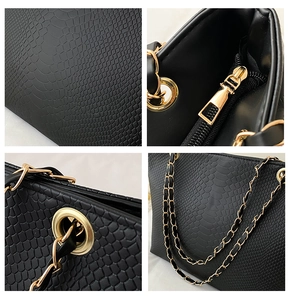 Close-up of black crocodile texture leather with gold hardware and chain strap details