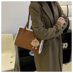 Détail du grand sac cabas marron avec bordure en peluche blanche et charme de monstre