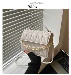 Close-up of white quilted PU leather handbag featuring decorative resin chain links
