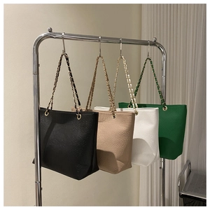 Detail view of four crocodile-patterned tote bags in black, beige, white, and green tones