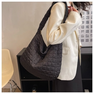 Quilted puffer shoulder bag in black with soft cloud-like texture shown on model