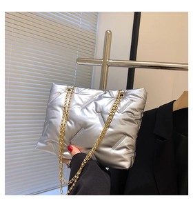 Detail der silbernen gesteppten Puffer-Tasche mit Metallic-Finish und Goldkette