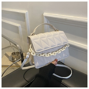 Detail of cream white quilted handbag with glossy finish and resin chain decoration