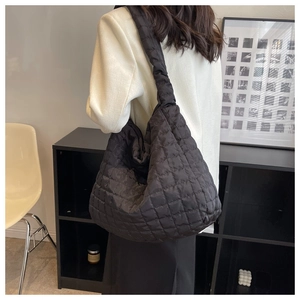 Macro detail of black quilted puffy tote bag featuring textured diamond stitching patterns