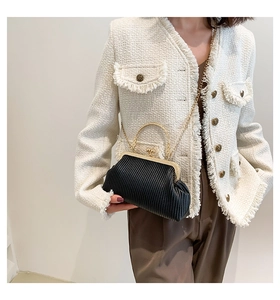 Details einer schwarzen Plissee-Clutch mit goldenem Metallrahmen und Kette am Modell