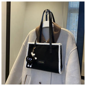 Détail du sac cabas noir avec bordure en fausse fourrure blanche et breloque pompon