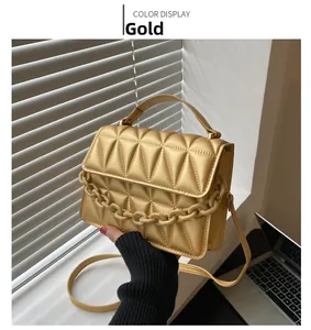 Detail of gold quilted handbag with geometric pattern and chunky chain handle