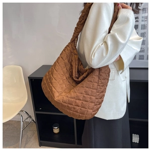 Brown quilted space cotton puffer bag with a wide strap shown on a model's shoulder
