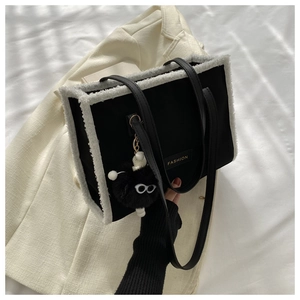 Détail du sac fourre-tout noir avec bordure en fausse fourrure et breloque peluche
