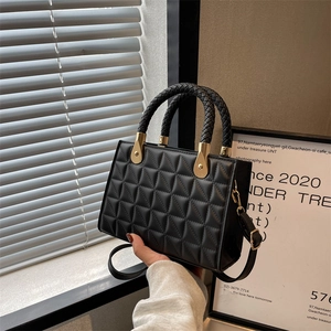 Quilted black leather handbag with braided handle and gold hardware on minimalist background
